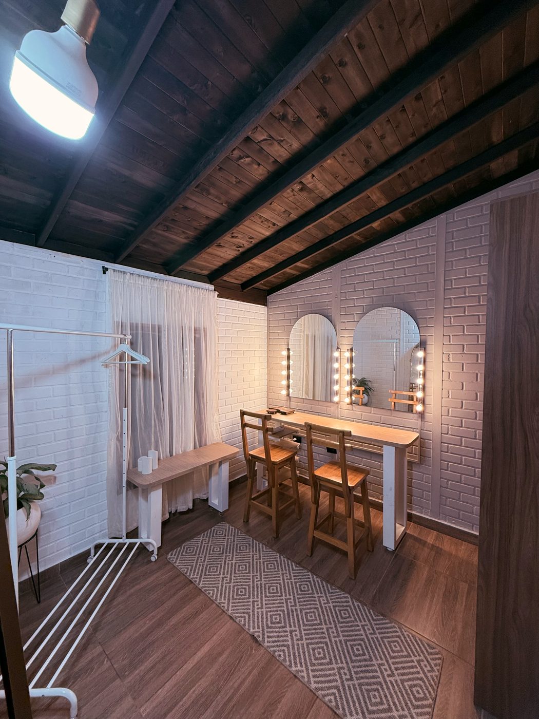 Backstage de Casa Armonía con tocador iluminado, rack y techo de madera